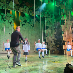 Matilda cast cheer on England's Lionesses. Girls on swings pictured on stage wearing the women's England football kit.