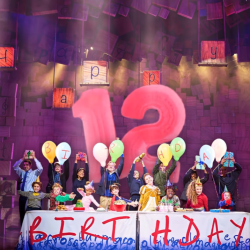 Celebrate 12 years of Matilda - some of the cast are pictured having a birthday party with a big number 12 behind them.