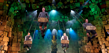 Adult company of Matilda The Musical on swings during the 'When I Grow Up' scene