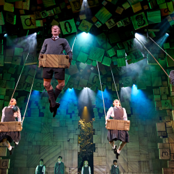 Adult company of Matilda The Musical on swings during the 'When I Grow Up' scene